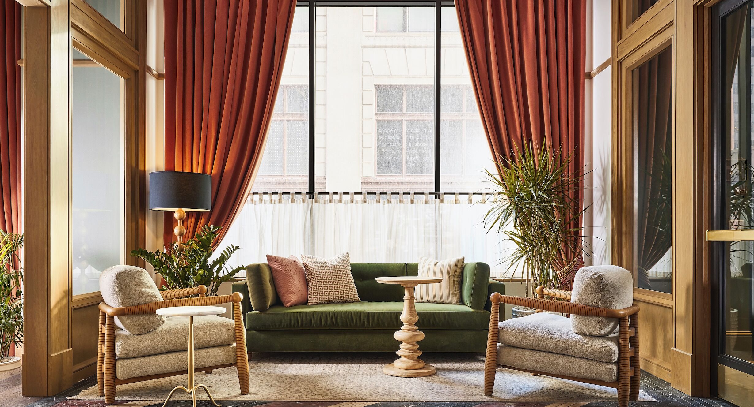Ein Zimmer mit einem grünen Sofa, zwei Sesseln, einem kleinen Tisch und einer Stehlampe.