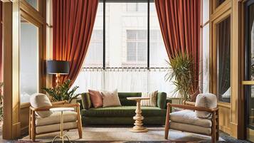 Ein Zimmer mit einem grünen Sofa, zwei Sesseln, einem kleinen Tisch und einer Stehlampe.