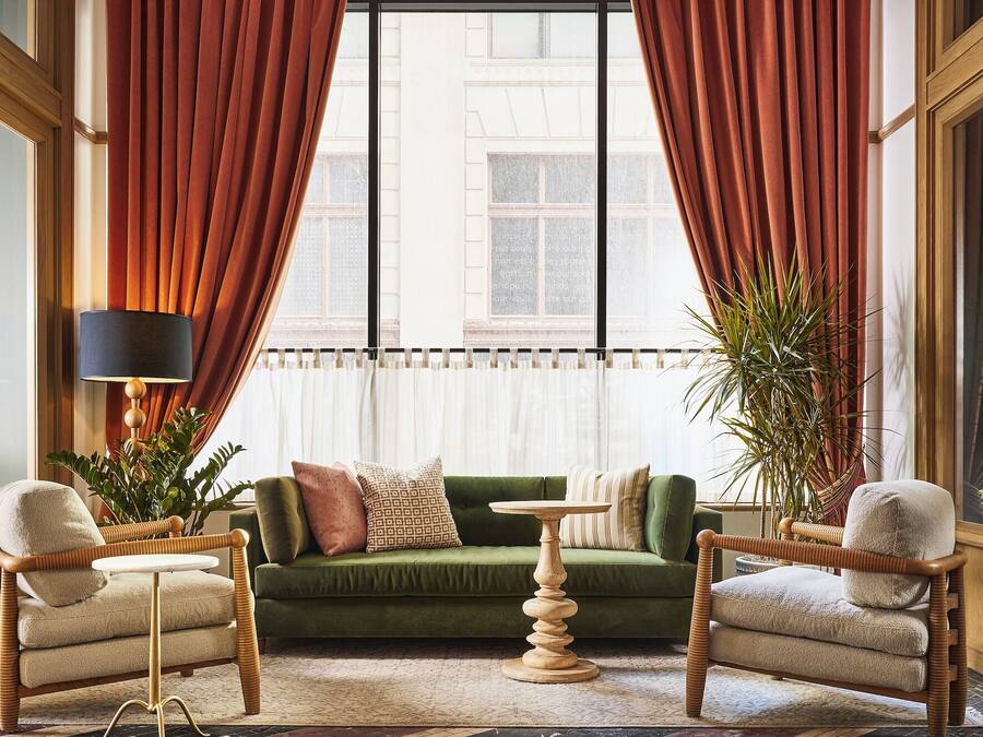 Ein Zimmer mit einem grünen Sofa, zwei Sesseln, einem kleinen Tisch und einer Stehlampe.