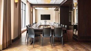 Una sala conferenze con un lungo tavolo, sedie, un televisore a schermo piatto e un lampadario.