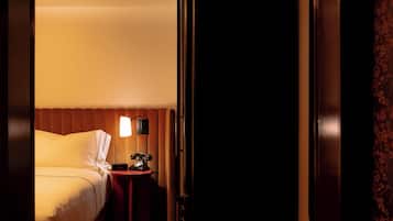 Una habitación de hotel con cama, mesita de noche con lámpara y un banco.
