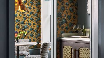 A room with a checkered chair, a table with a vase, and a cabinet with patterned doors.