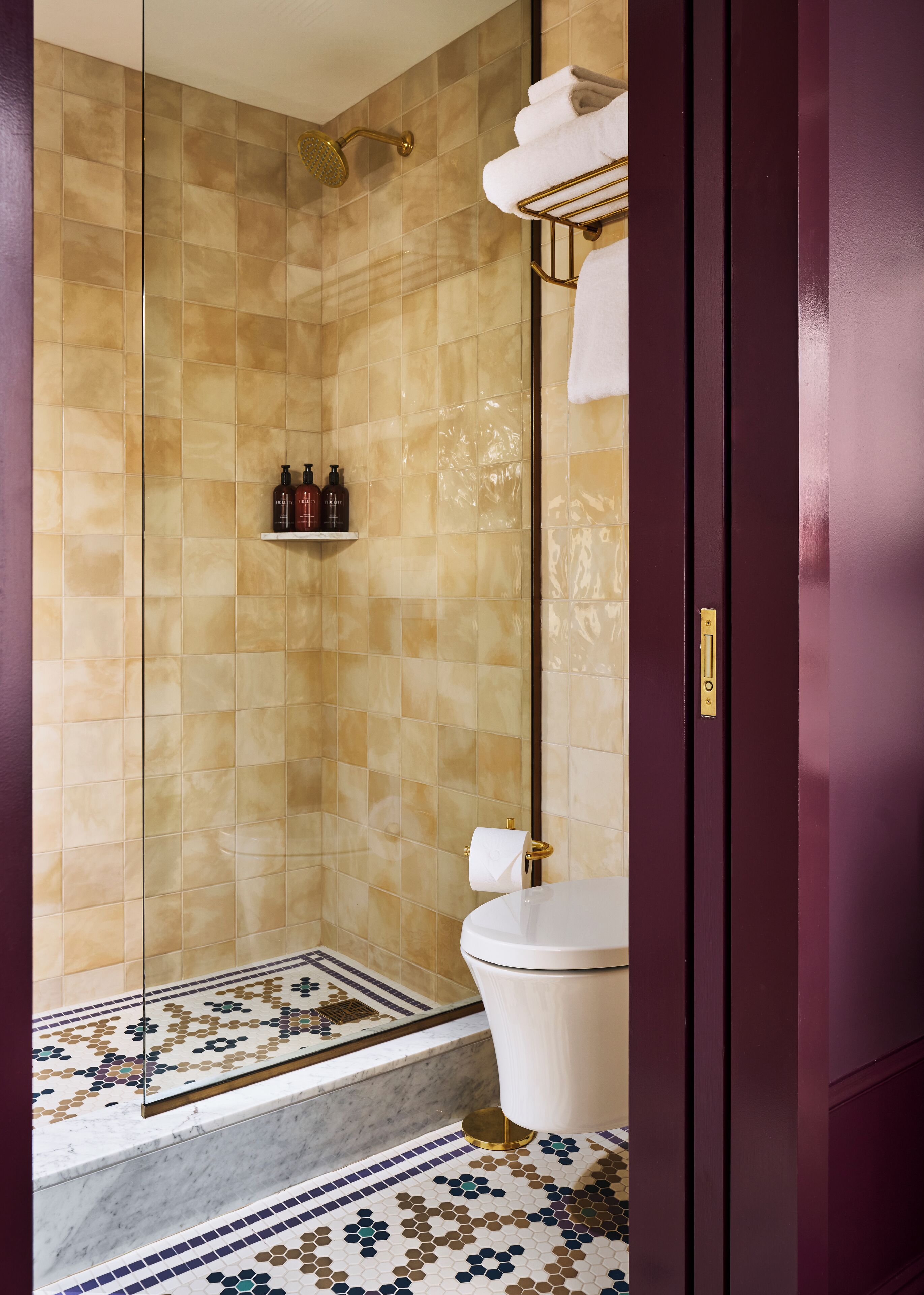 A bathroom with a shower, toilet, and a tiled floor.