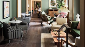 Un'ampia hall dell'hotel con arredi a righe, un arco centrale e una sala da pranzo sullo sfondo.