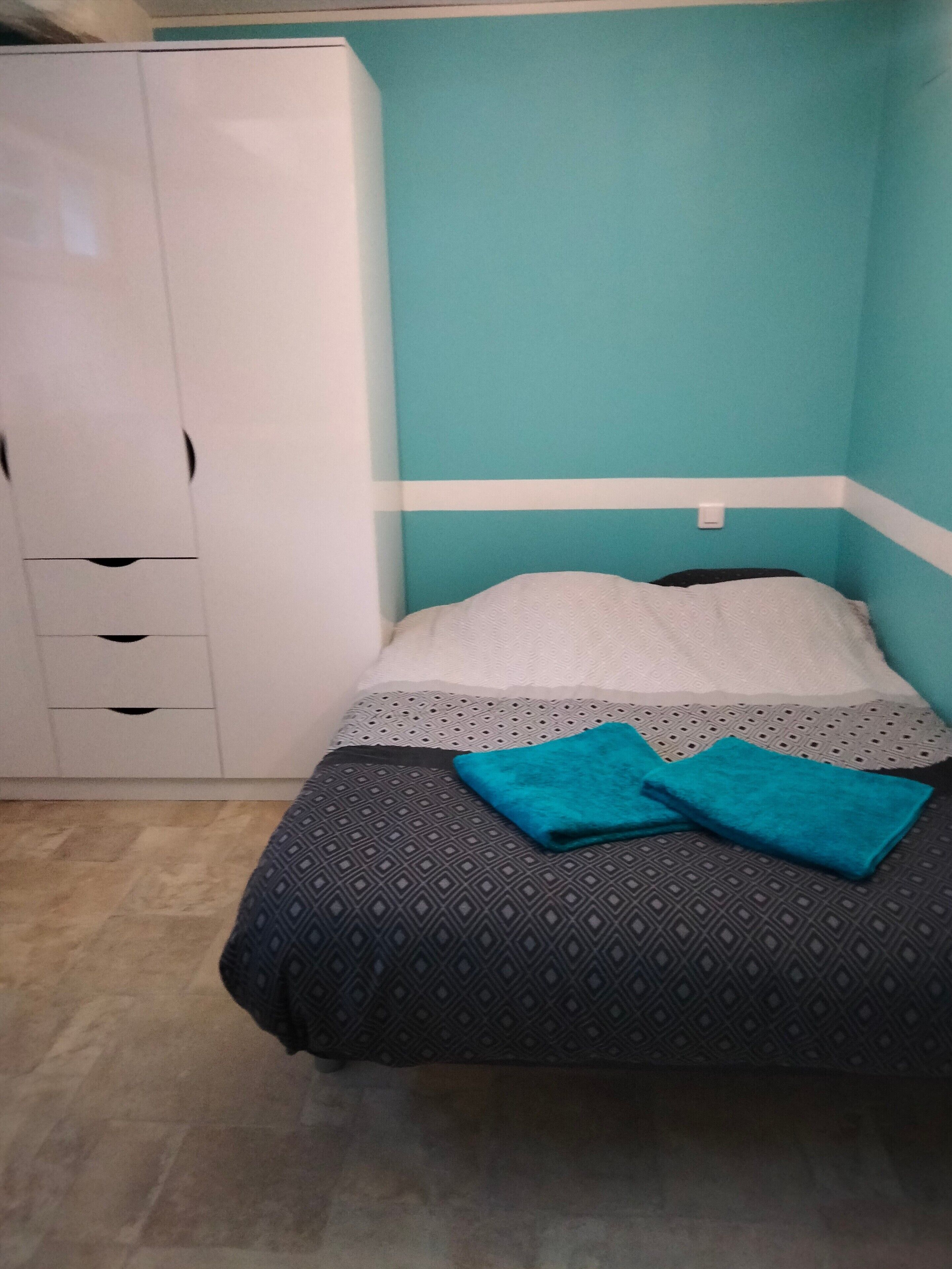 Un dormitorio con cama, armario y una pared a rayas.