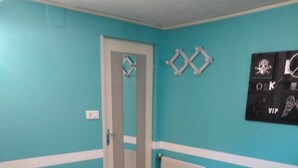 Habitació amb dos llits, una porta, un radiador i una paret amb elements decoratius.