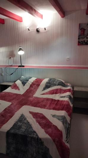 Una camera da letto con un letto, una scrivania e una sedia. Sono presenti due lampade a parete.