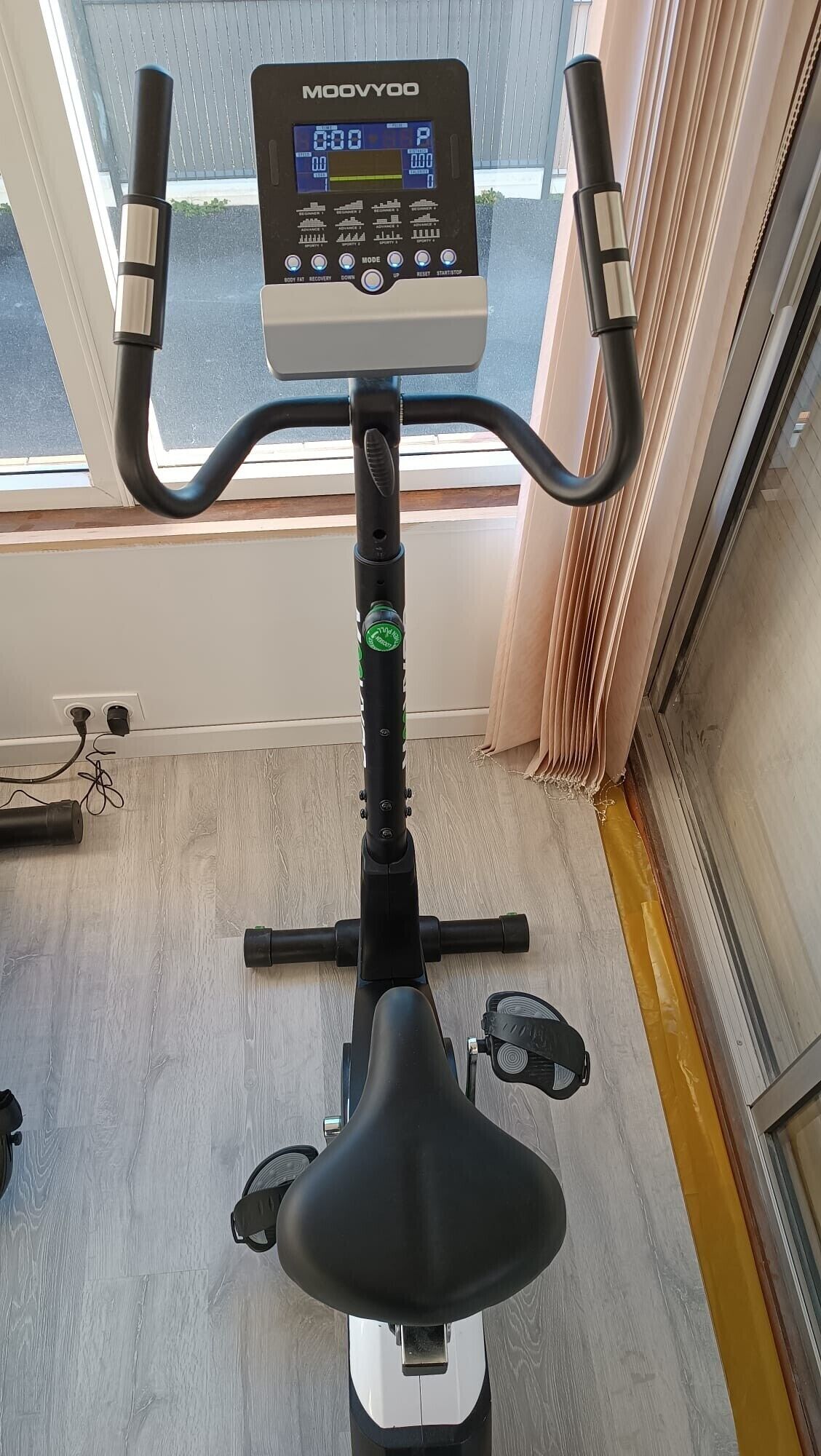 An exercise bike with a digital display, positioned indoors near a window.