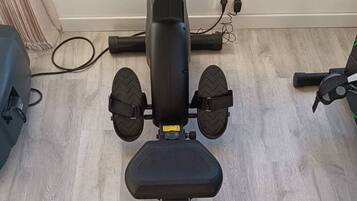 A stationary exercise bike with a digital display, a white seat, and a black footrest.