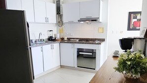A modern kitchen with white cabinets, a black refrigerator, and a wooden countertop. - PARCEROS GROUP - 2 BEDROOM VACATION APARTMENT, 6TH FLOOR, CARTAGENA, SPAIN (Cartagena de Indias)