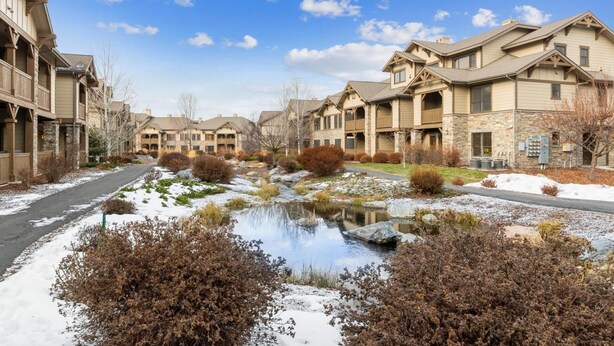 Un quartier résidentiel avec de nombreuses maisons à deux étages, un petit étang et un ciel dégagé.