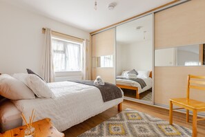 Relax in this serene bedroom with a large bed, a comfortable chair, and a stylish wooden table.