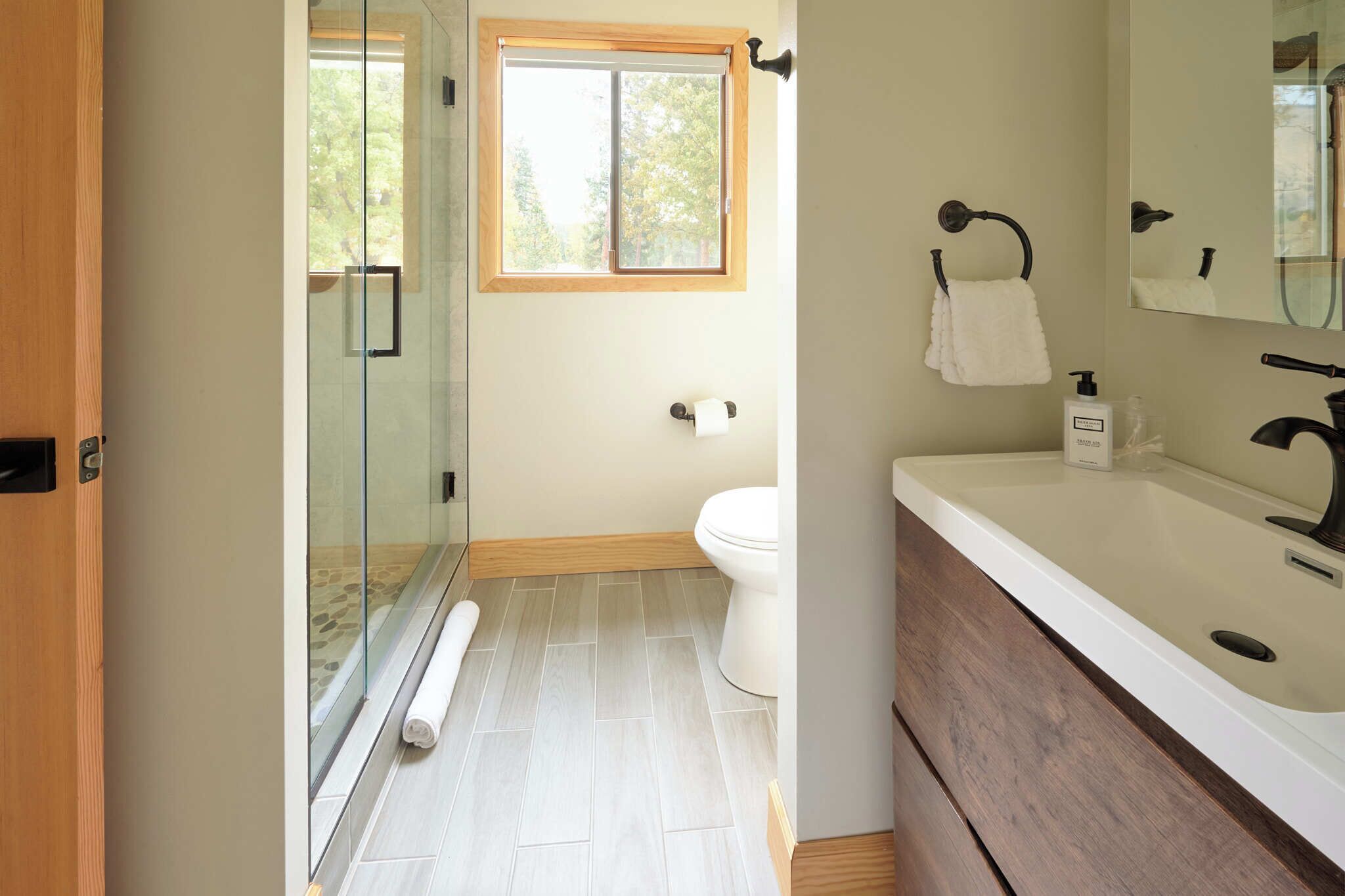A modern bathroom with a glass shower enclosure, a toilet, and a sink with a mirror.