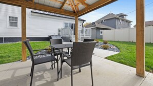 Eine Terrasse im Freien mit überdachter Sitzgelegenheit, einem Tisch und Stühlen.