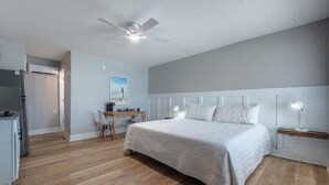 Une chambre à coucher comprenant un lit, un bureau, une chaise et un ventilateur de plafond.