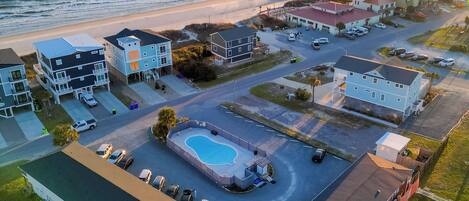 Vista aérea de un hotel costero con piscina, acceso a la playa y un muelle en el fondo.