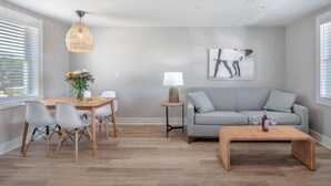 Una sala de estar moderna con una mesa de comedor, un sofá gris y una mesa de centro.