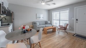 Un salon moderne avec un canapé gris, une table basse et un coin repas comprenant une table ronde et des chaises.