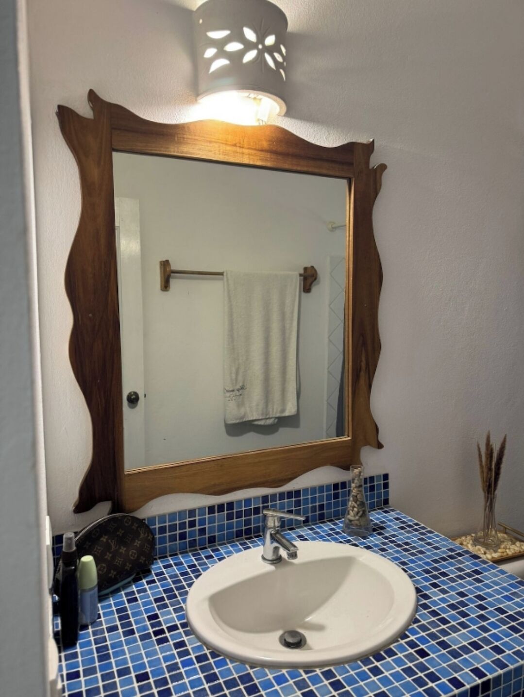 Une salle de bain avec un miroir à cadre en bois, un lavabo blanc et des carreaux de mosaïque bleus.