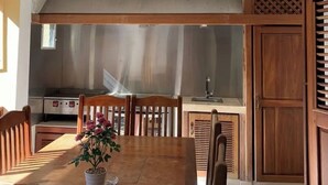 A dining area with a wooden table, chairs, a ceiling fan, and a kitchen in the background. - villa ji (Las Terrenas)