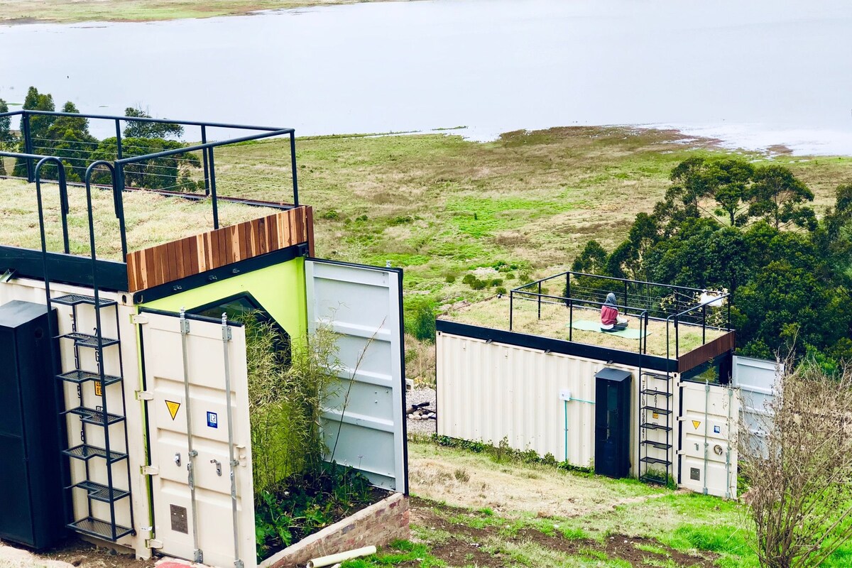 A modern building with a rooftop garden, a small deck, and a view of a lake.