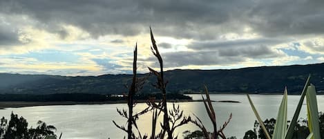 Un lago con montañas al fondo y cielo nublado.