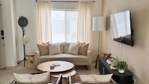 Un salon moderne comprenant un canapé, deux fauteuils, une table basse, un téléviseur et un ventilateur de plafond.