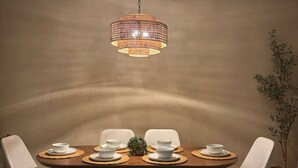 Un espace repas comprenant une table ronde, quatre chaises, un banc et un luminaire suspendu.