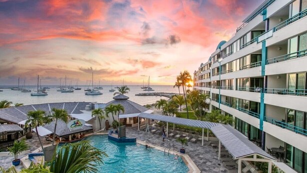 Un hôtel doté d'une piscine, d'un espace extérieur aménagé et offrant une vue sur la mer au coucher du soleil.