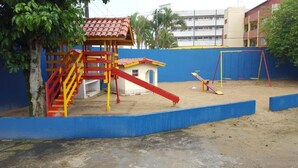 Un parque infantil con tobogán, estructura para escalar y columpios.