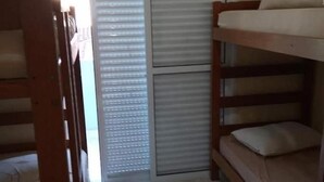 Un dormitorio con literas, una puerta corredera y suelo de baldosas.