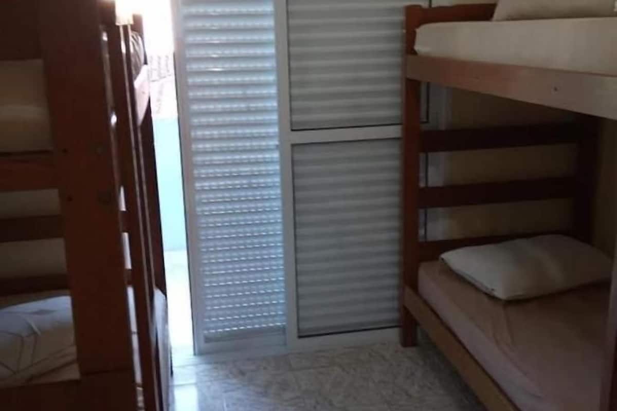 A dormitory room with bunk beds, a sliding door, and a tiled floor.