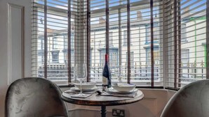 Une pièce avec une table ronde, deux chaises, une bouteille et des verres à vin.