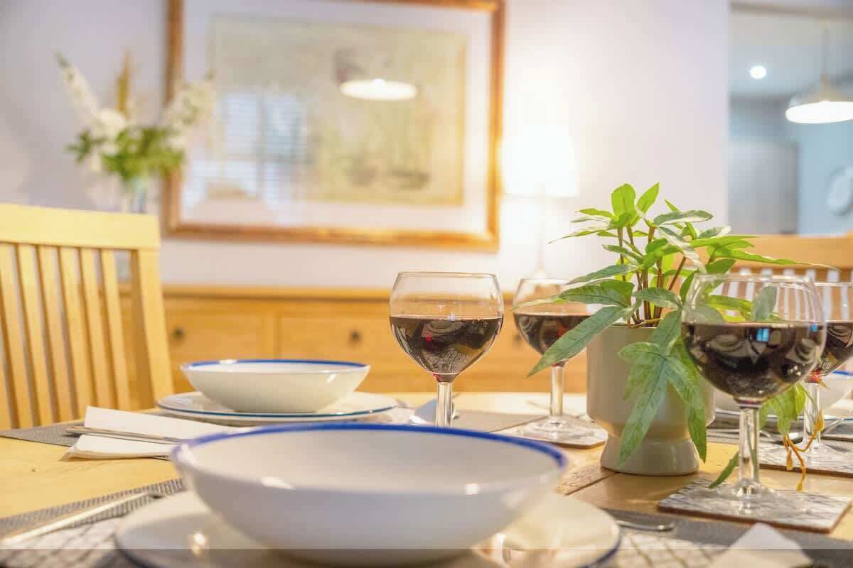 A dining table with plates, glasses, and a potted plant.
