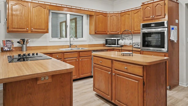 A kitchen with wooden cabinets, a stainless steel oven, a microwave, and a sink. - Spacious & Lovely 4-BR Home Minutes to WEC, HITS (Ocala)