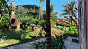 Une terrasse en pierre avec un palmier, un four en briques et une piscine.
