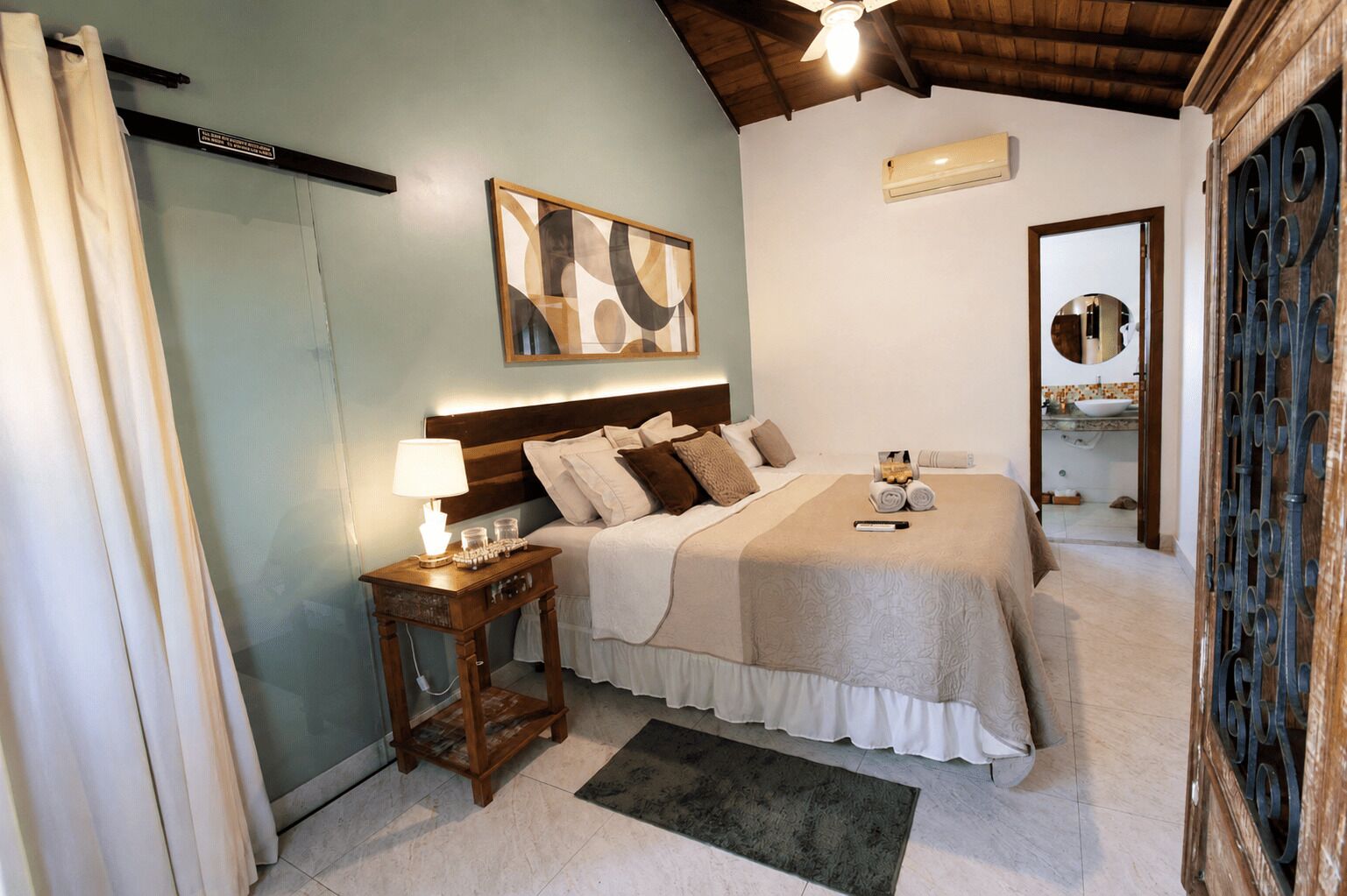 A bedroom with a bed, bedside table, lamp, and a painting on the wall.