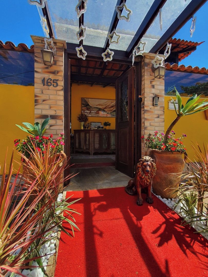 A building entrance with a red carpet, a dog statue, and potted plants.