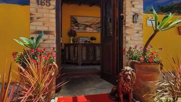A building entrance with a red carpet, a dog statue, and potted plants.