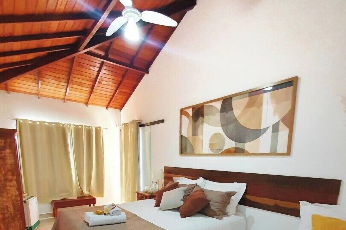 Quarto de hotel com duas camas, um ventilador de teto, um quadro e vista para o exterior.