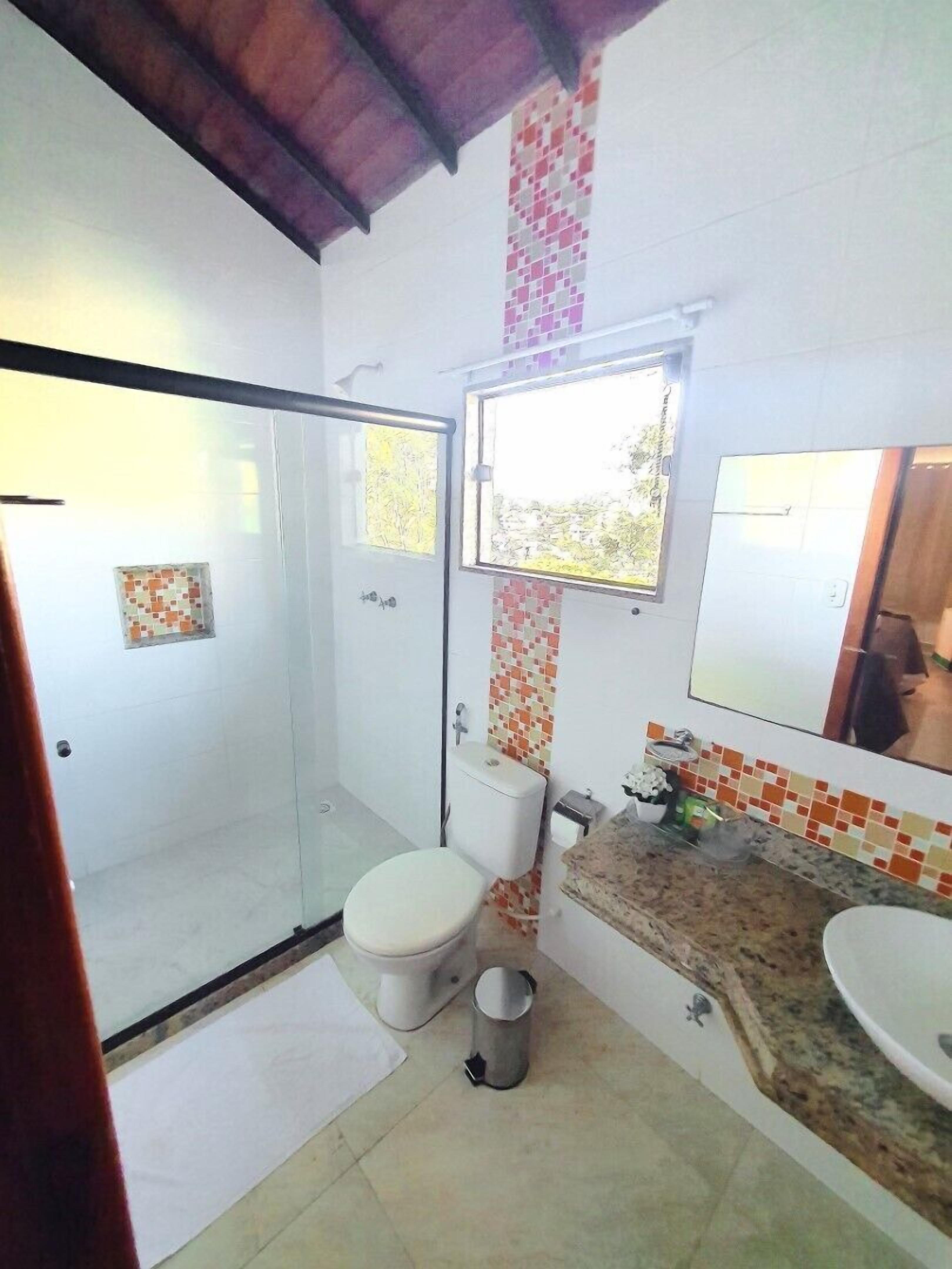 Un bagno con doccia, toilette, lavandino e finestra.