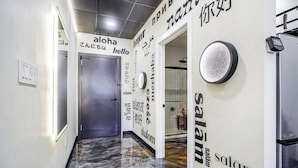 Un pasillo con piso pulido, una puerta y una pared con texto multilingüe que incluye 'hello' y 'Salam'.