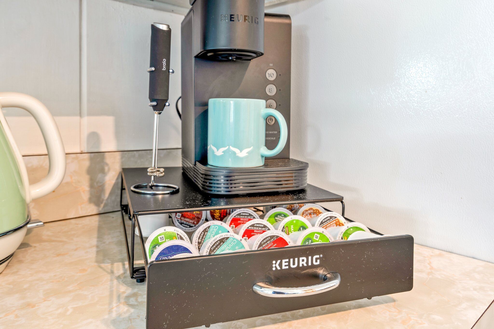 Máquina de café Keurig com uma caneca e gaveta para cápsulas de café.