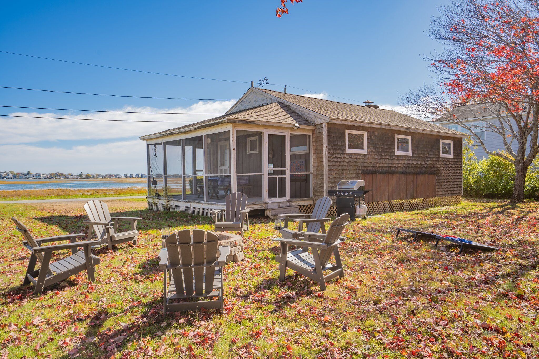 A house with a porch, outdoor seating, and a view of the water.