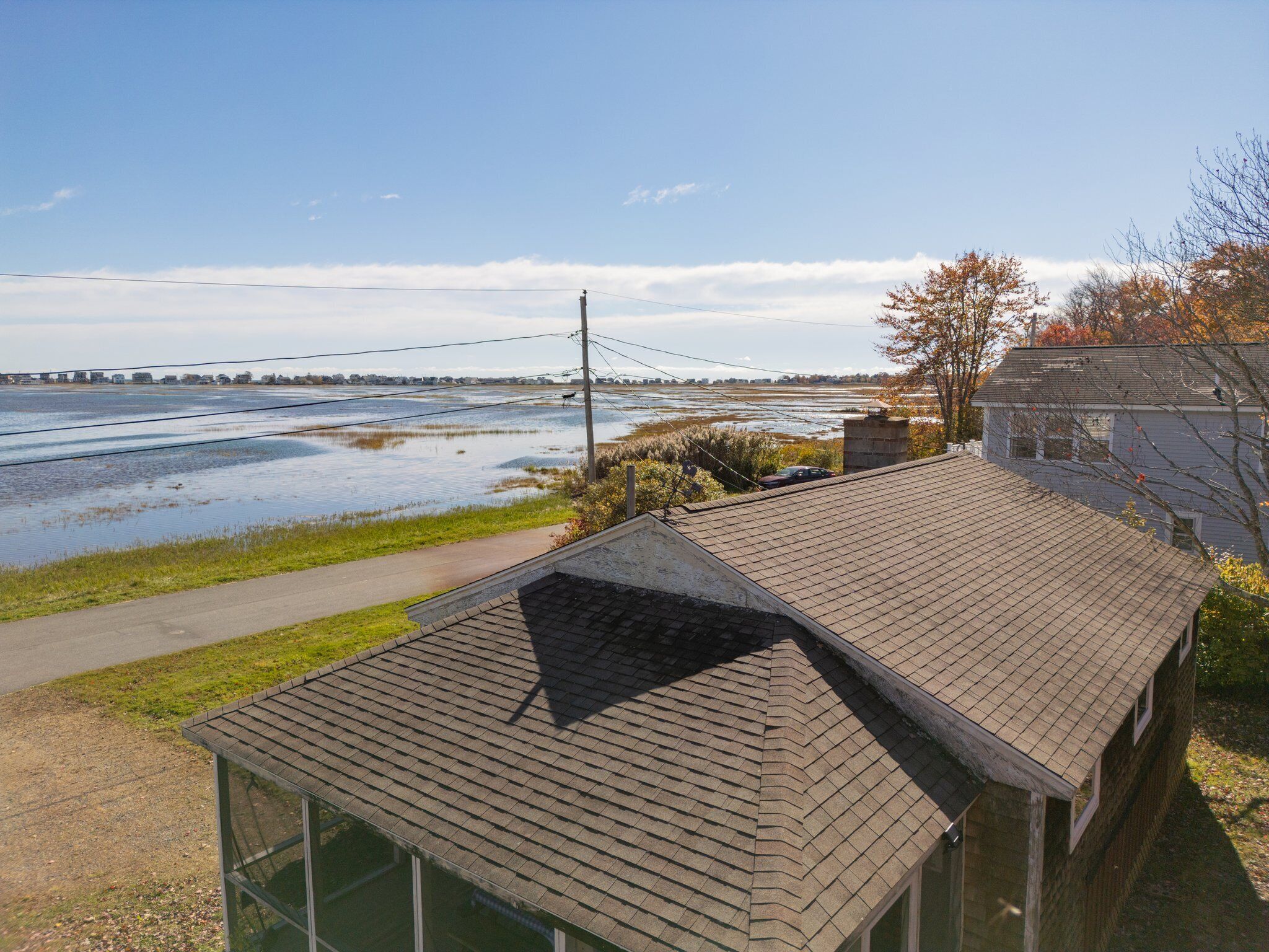 A house with a sloped roof, a visible chimney, and a paved pathway leading to a body of water.
