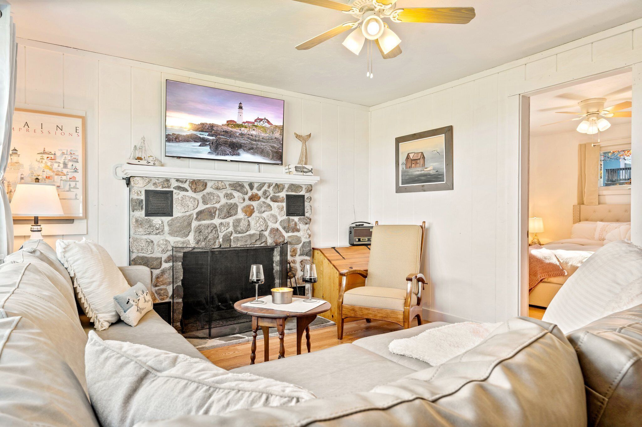 A cozy living room with a stone fireplace, a television mounted above it, and a comfortable seating area with a sofa and armchairs.