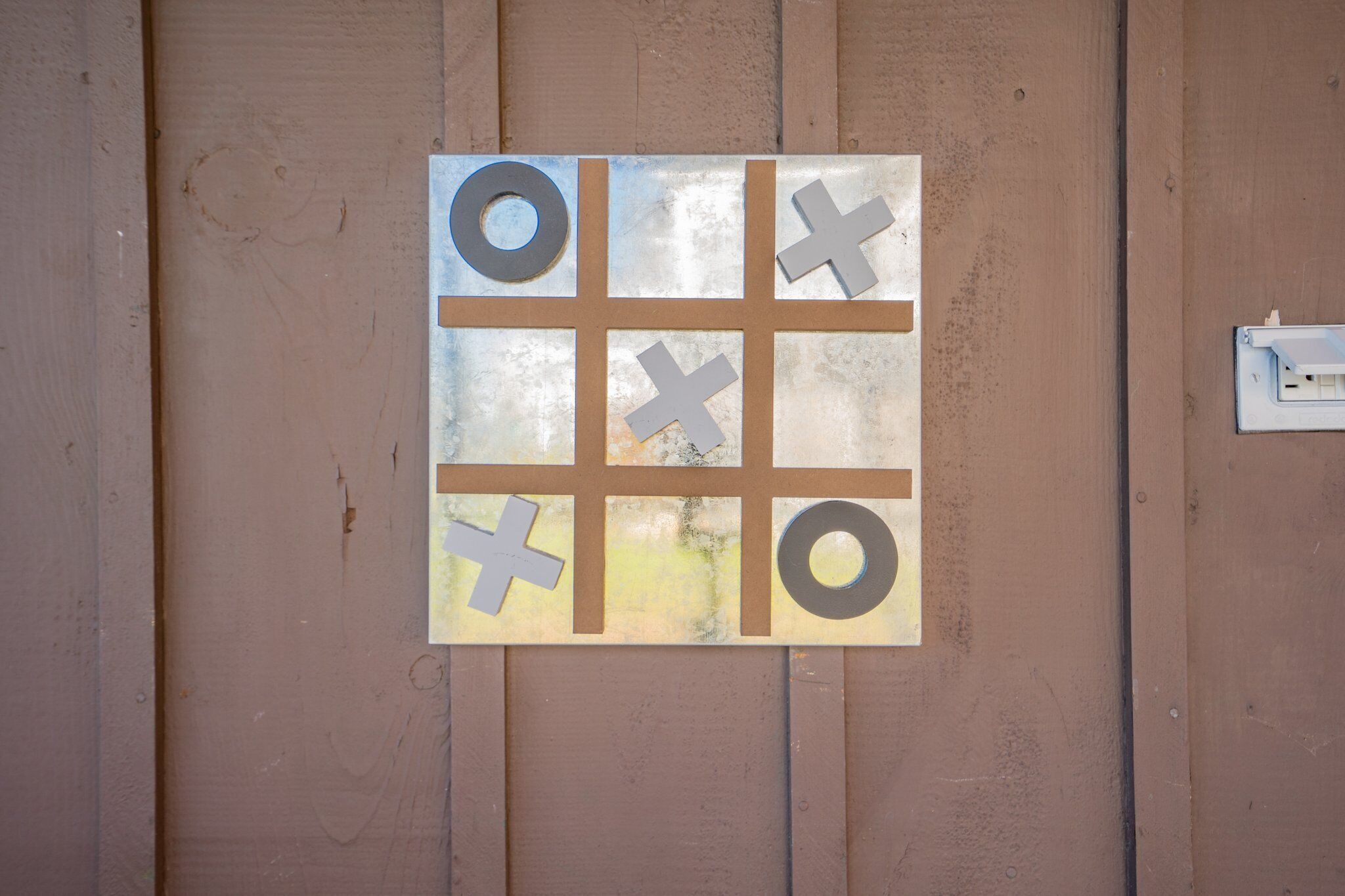 Een tic-tac-toe spelbord bevestigd aan een houten muur.