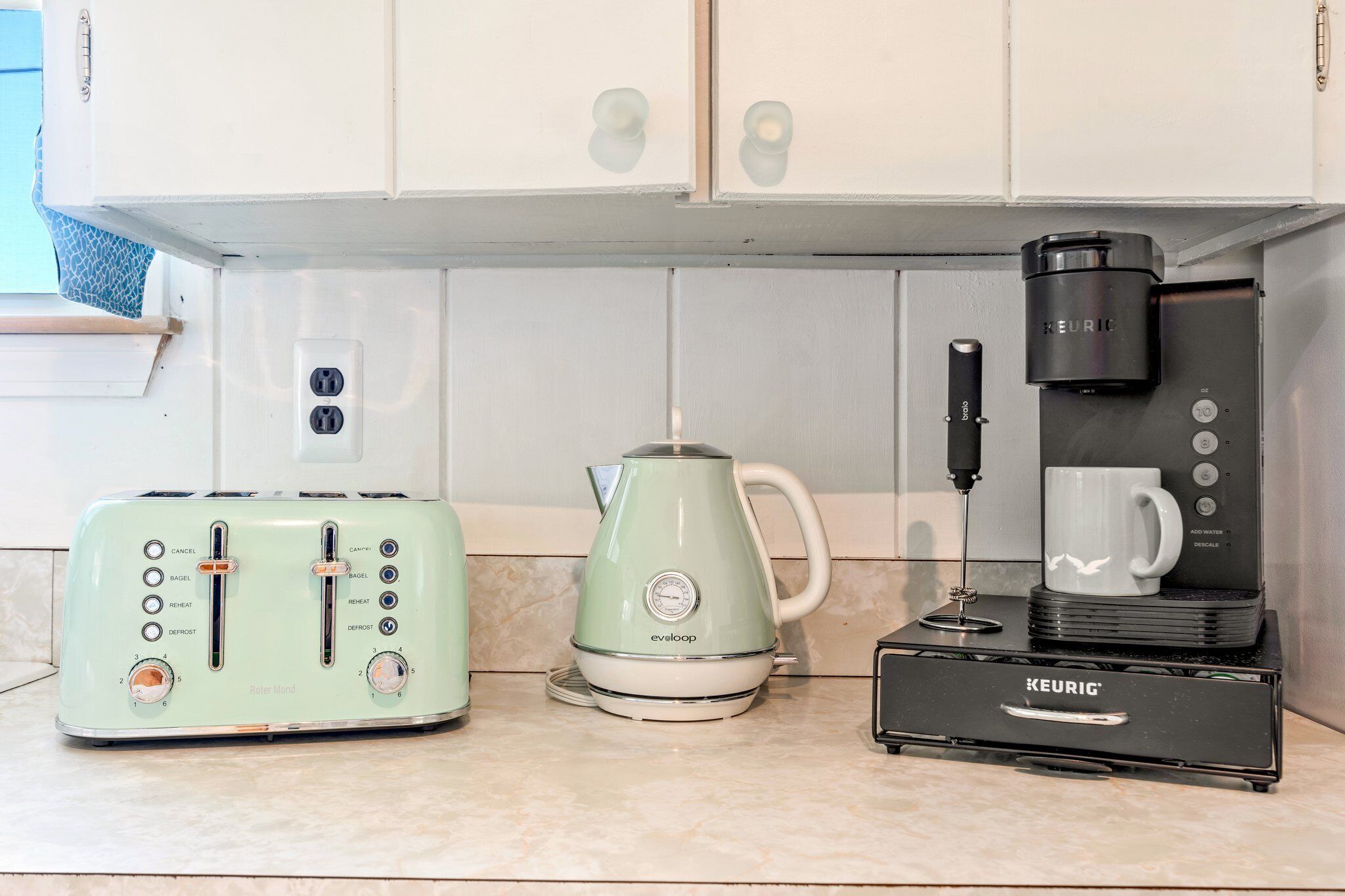 A kitchen with a toaster, a kettle, and a coffee maker.
