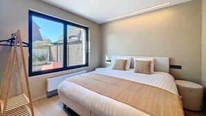 A modern bedroom with a large bed, a wooden ladder, and a view of the outside.