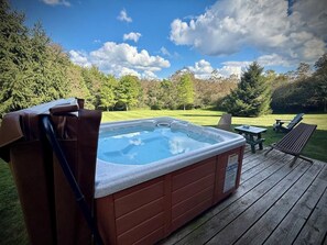 A hot tub on a wooden deck with a grassy yard and trees in the background. - Fernwood | Secluded | Deep Creek & Wisp | Hot Tub (Accident)